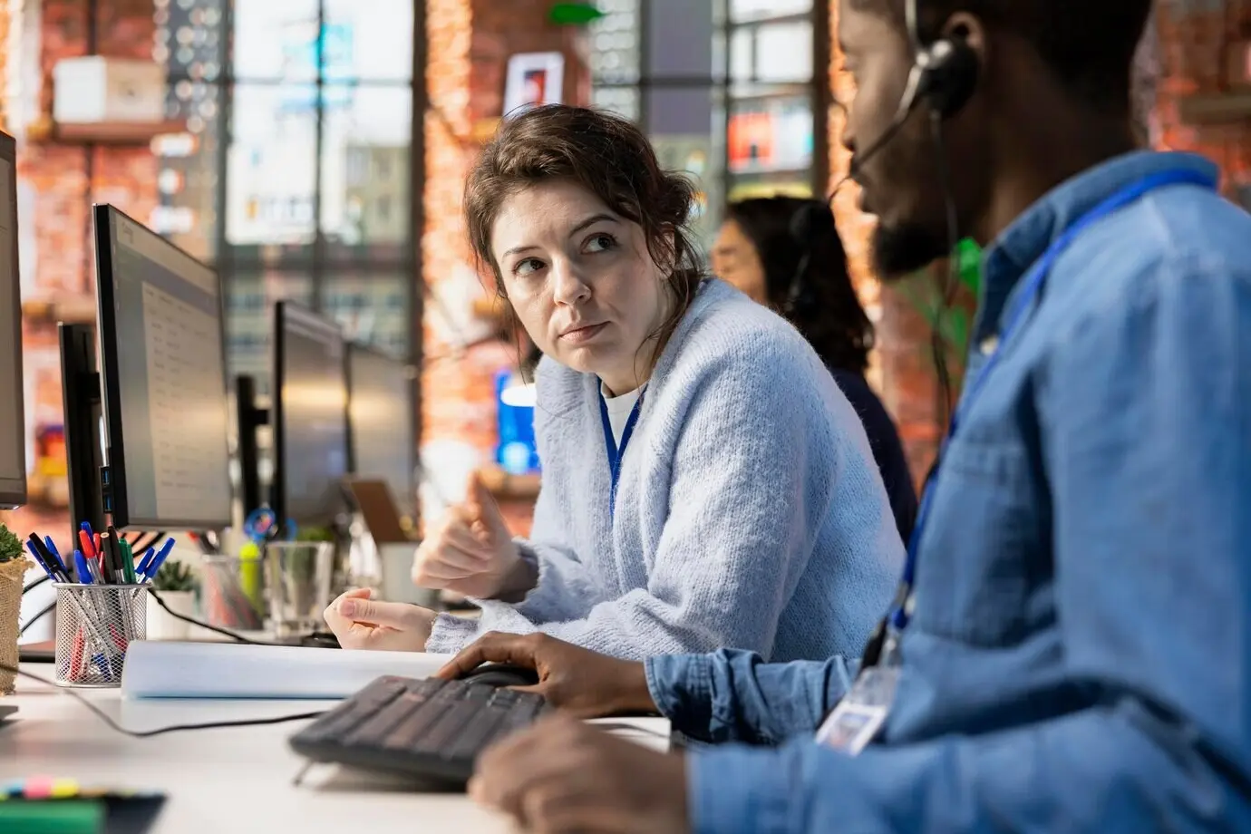 Ein Team von Callcenter-Agenten arbeitet zusammen und nutzt ein CSM-System am PC.